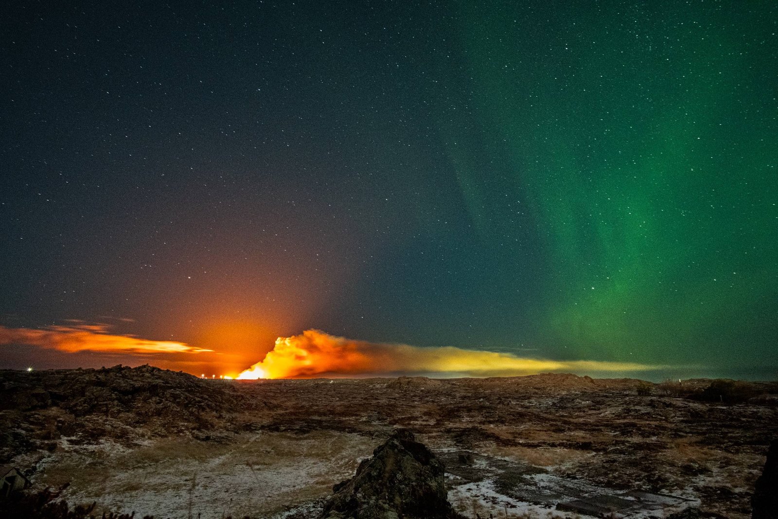 Aurora boreale sopra un'eruzione vulcanica in Islanda
