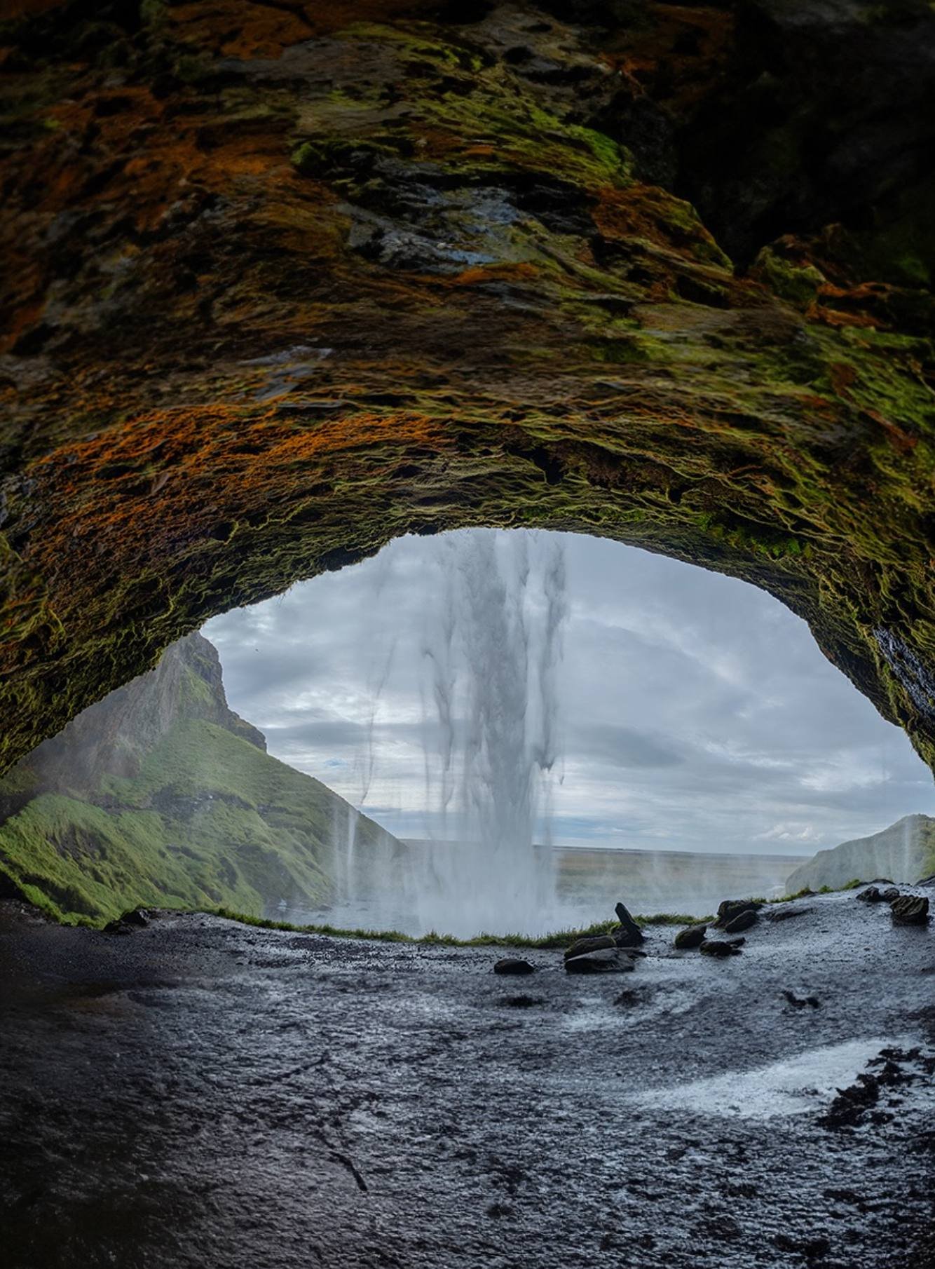 Una cascata in Islanda vista da una grotta con rocce ricoperte di muschio