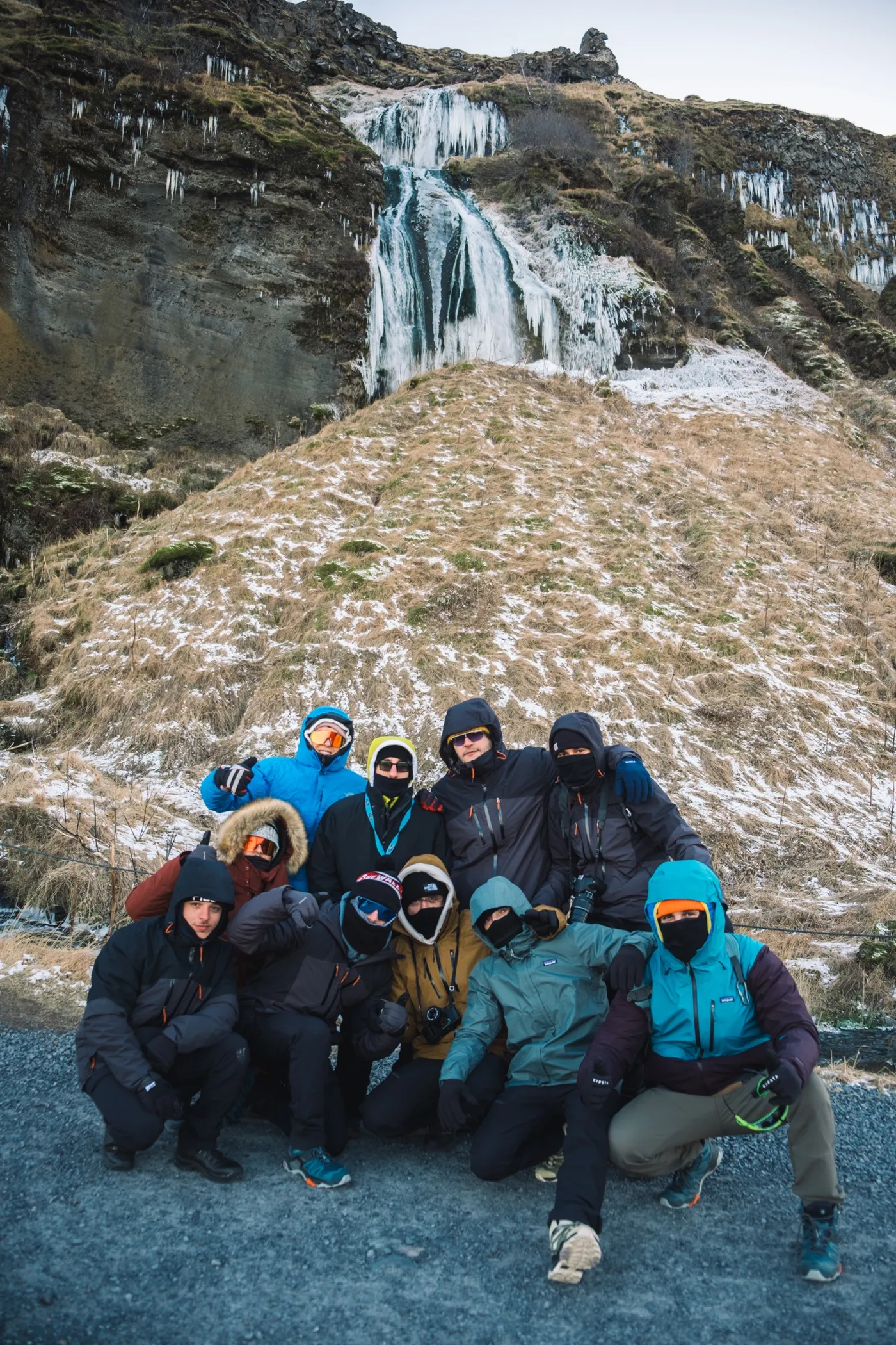 Il gruppo vestito per il freddo davanti a una cascata d'inverno