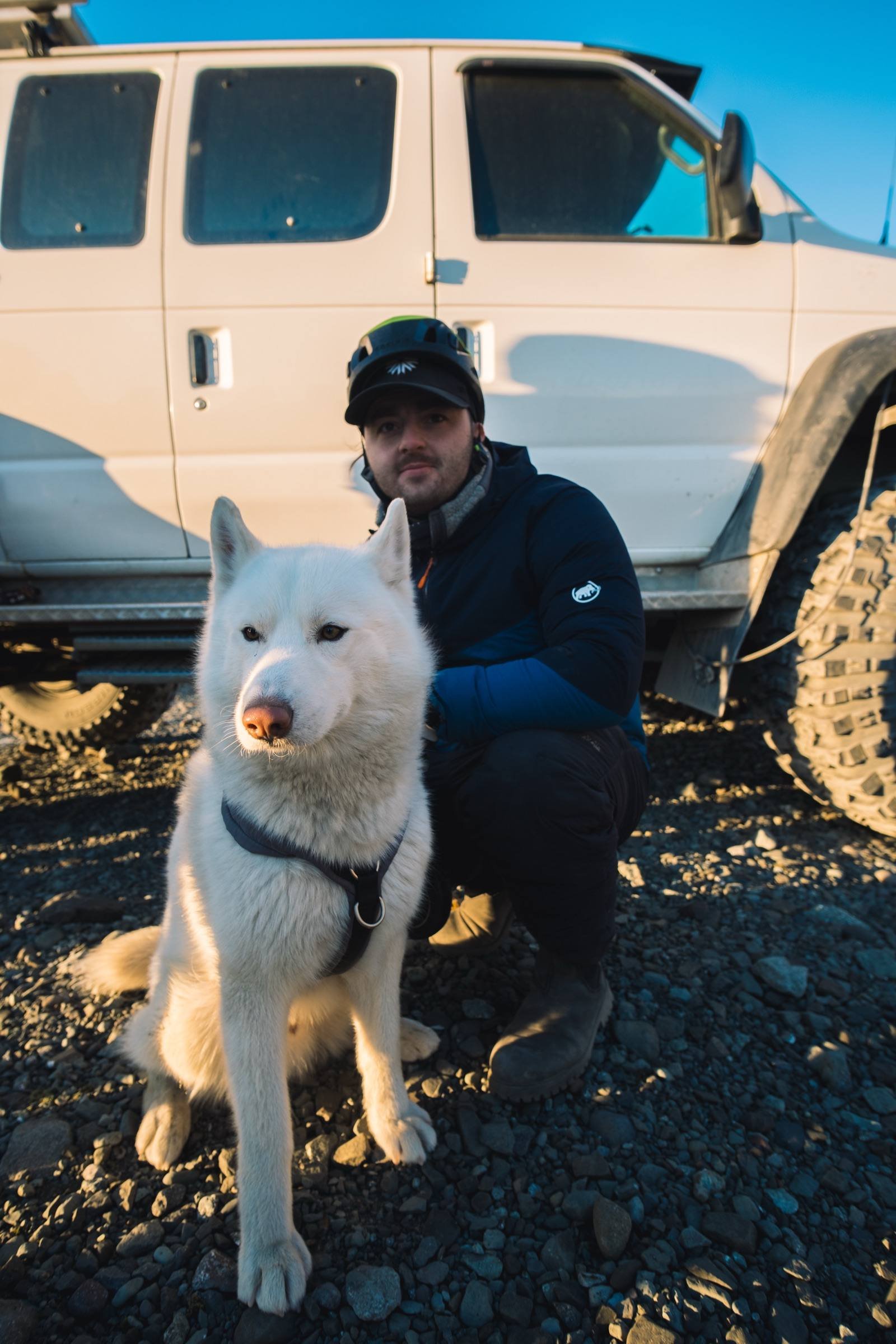 Viaggiatore con un husky accanto al 4x4 in Islanda