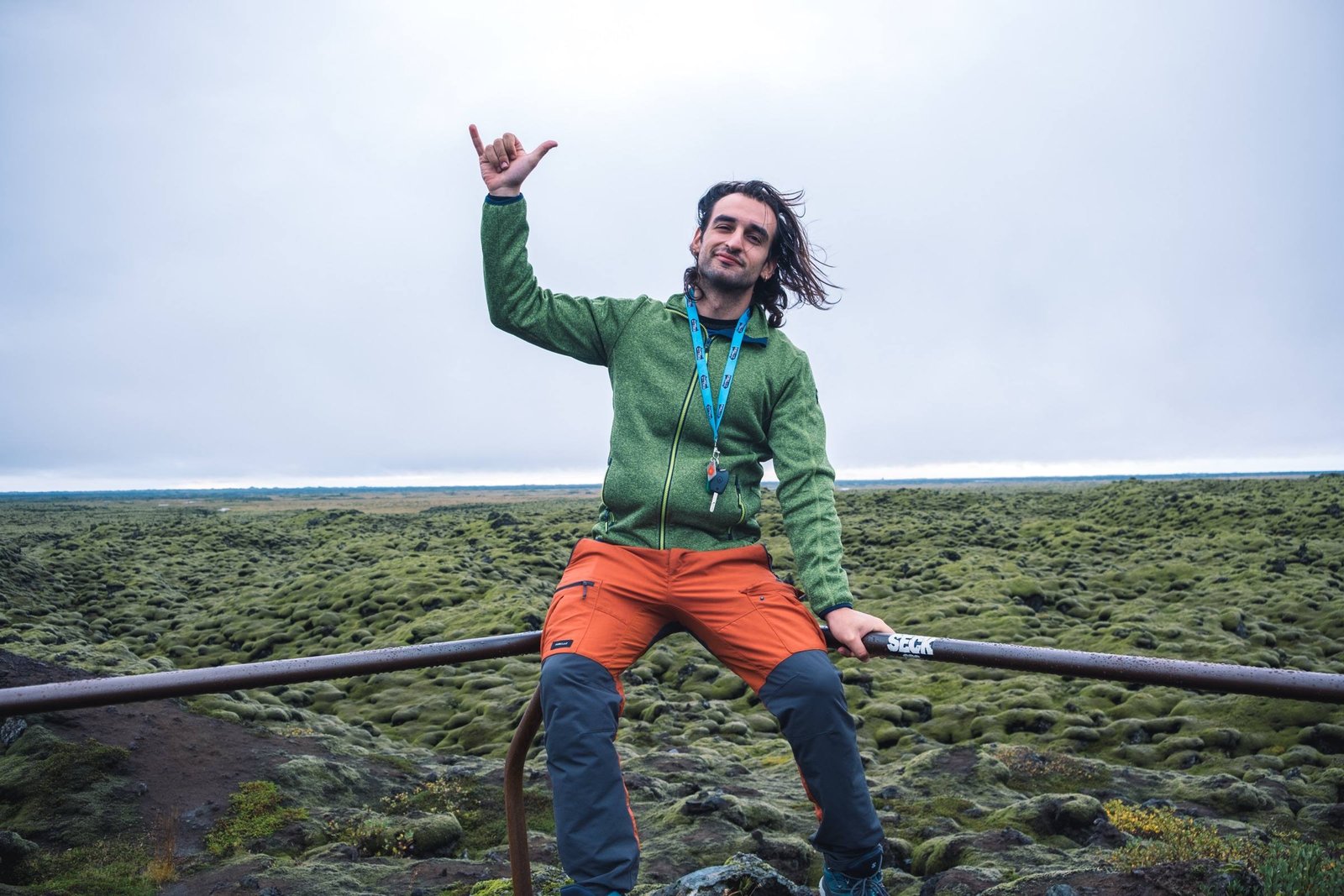 Un viaggiatore seduto su una ringhiera davanti a un campo di lava coperto di muschio in Islanda