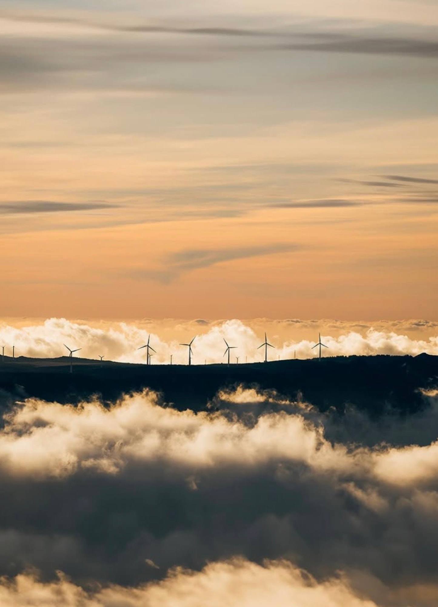 Pale eoliche su una cresta di Madeira sopra un mare di nuvole al tramonto