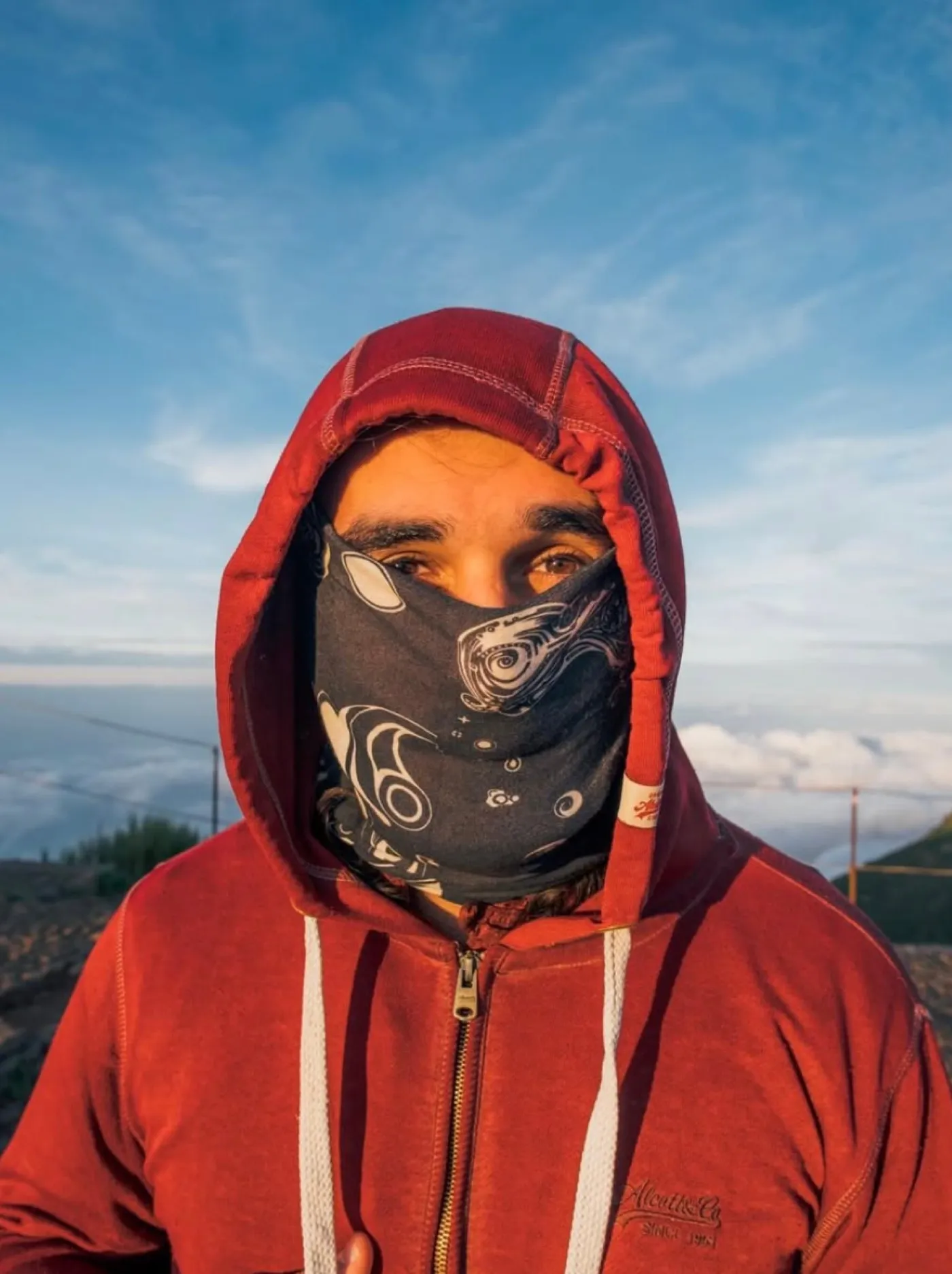 Un ragazzo con il cappuccio e lo scaldacollo controvento, sopra le nuvole a Madeira