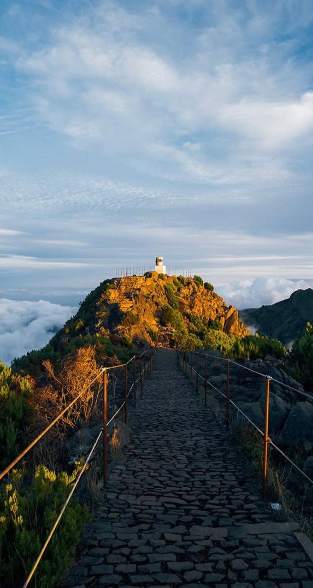 Un sentiero lastricato che porta a un faro sopra le nuvole a Madeira