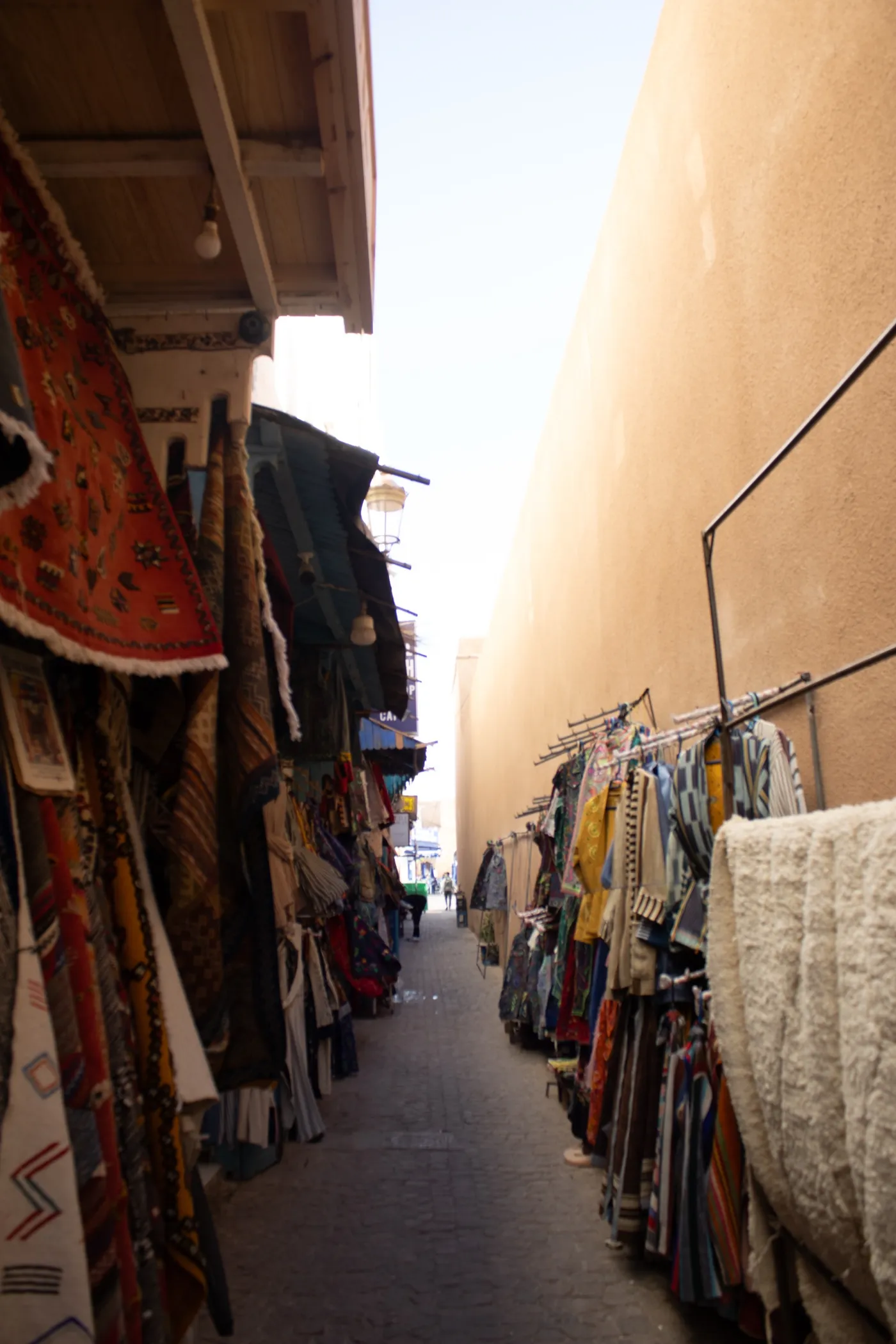 Un vicolo di un souk marocchino con tappeti e tessuti appesi