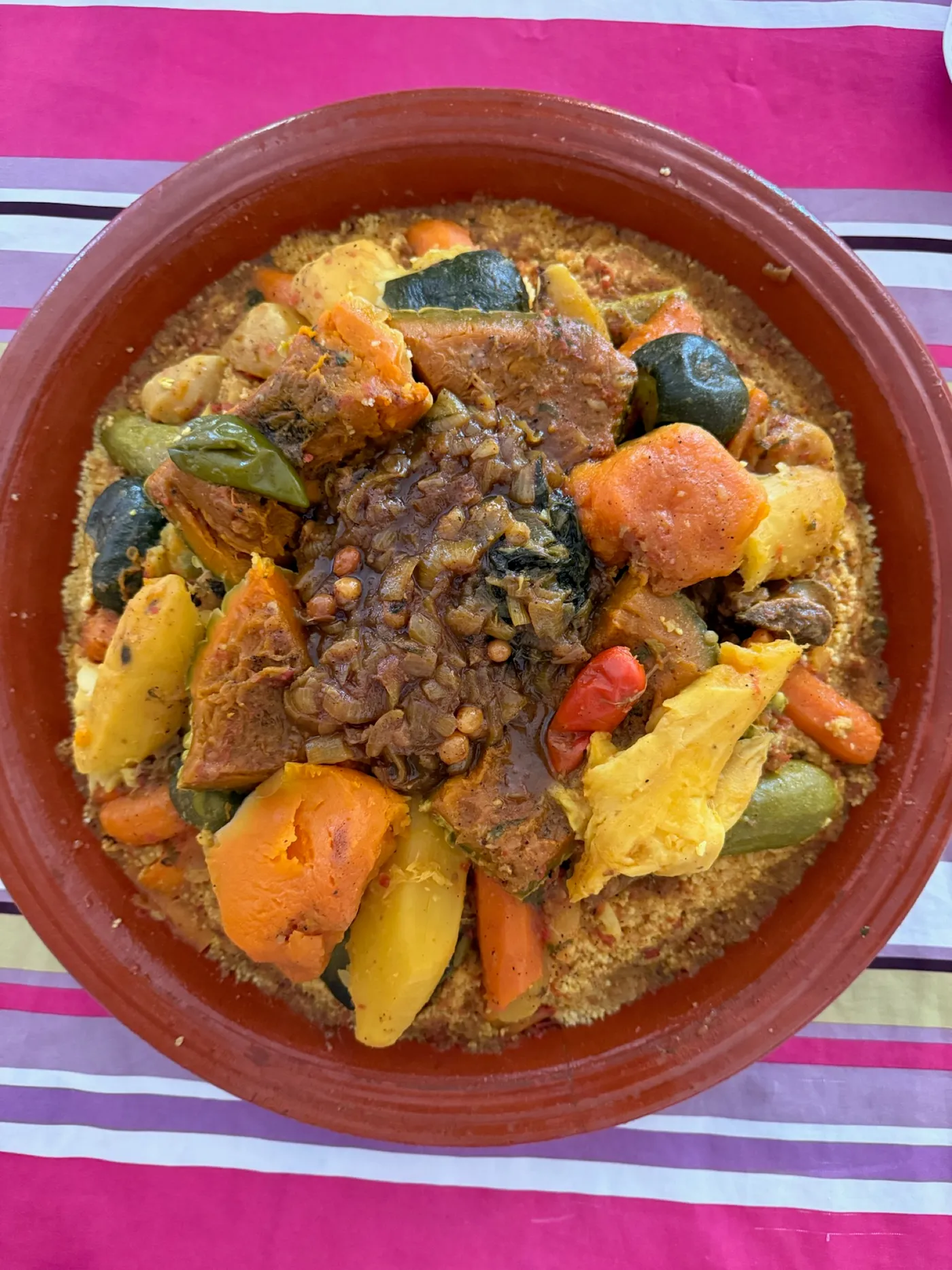 Una tajine di verdure su un tavolo con tovaglia a righe